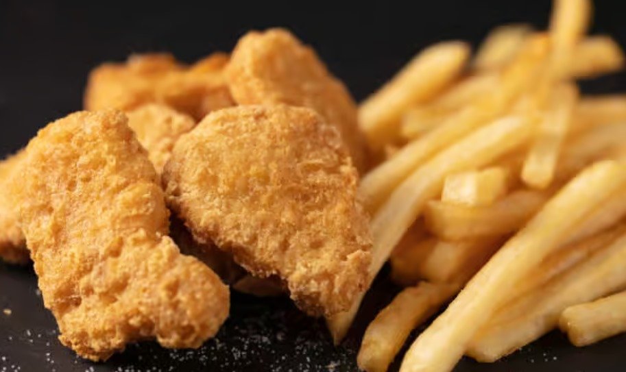 Chicken nuggets and french fries on a black background.